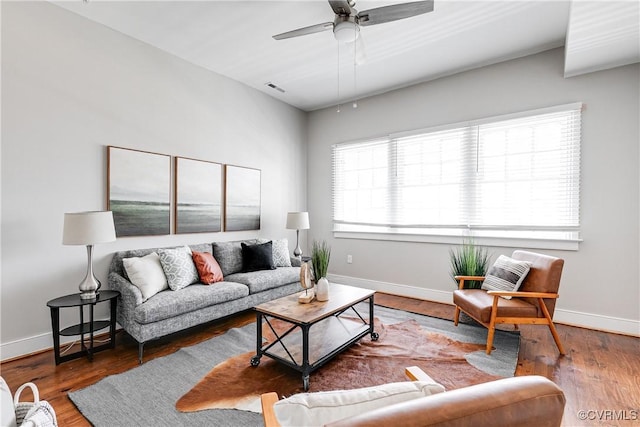 living area with wood finished floors, visible vents, baseboards, and ceiling fan