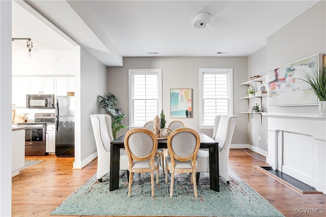 dining area with light wood-style floors, visible vents, and baseboards