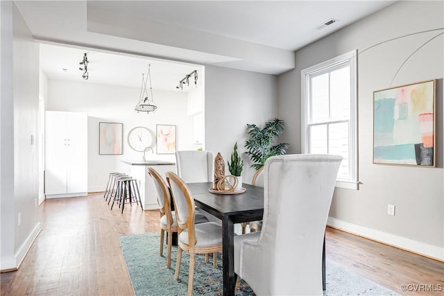 dining area featuring baseboards, light wood-style flooring, visible vents, and track lighting