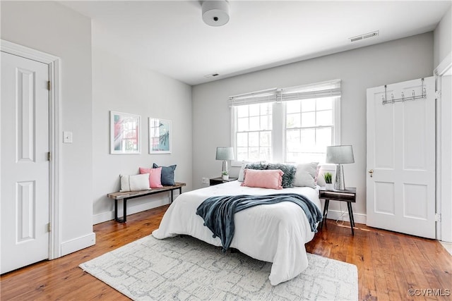 bedroom featuring baseboards, wood finished floors, and visible vents