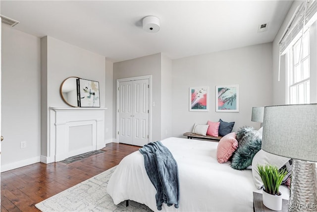 bedroom featuring baseboards, wood finished floors, visible vents, and a closet