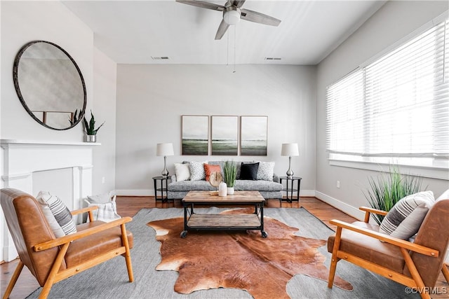 living room with baseboards, a ceiling fan, wood finished floors, and visible vents