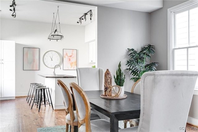 dining room with rail lighting, baseboards, and light wood-style flooring
