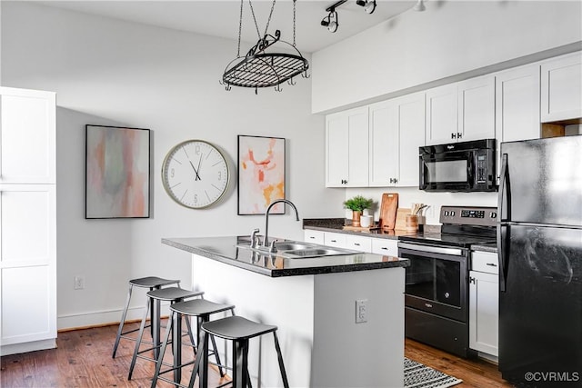 kitchen featuring a sink, a center island with sink, dark wood-style flooring, white cabinetry, and black appliances
