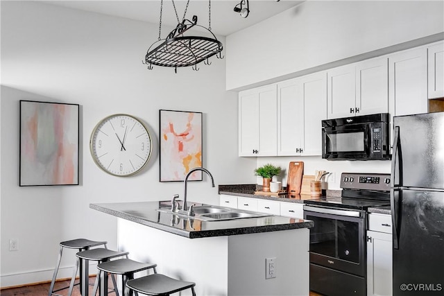kitchen with a kitchen bar, black appliances, a sink, and white cabinets