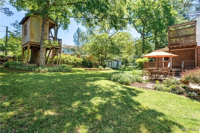 view of yard with stairs, a storage shed, a wooden deck, an outbuilding, and a patio
