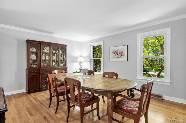 dining space with crown molding, baseboards, a healthy amount of sunlight, and light wood-type flooring