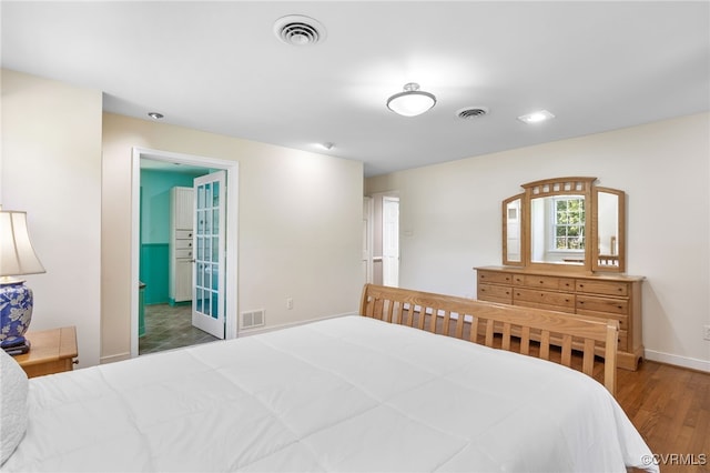 bedroom with visible vents, baseboards, and wood finished floors