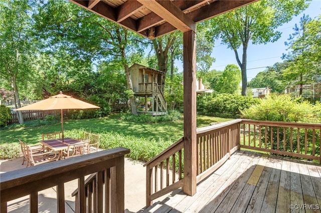 wooden terrace featuring outdoor dining area and a yard