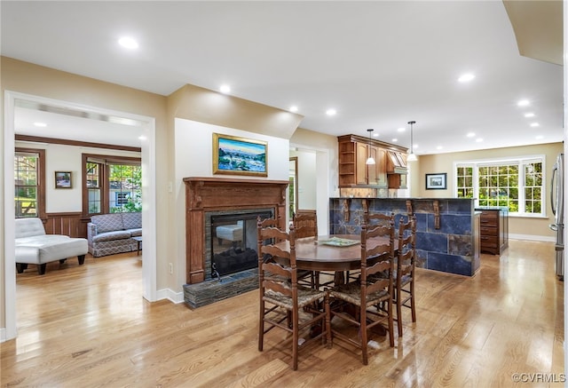 dining space with light wood-style floors, a glass covered fireplace, and recessed lighting
