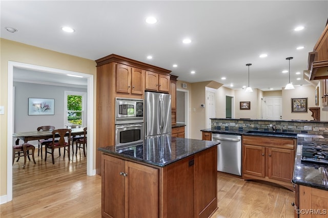 kitchen with a kitchen island, appliances with stainless steel finishes, a sink, and light wood-style flooring
