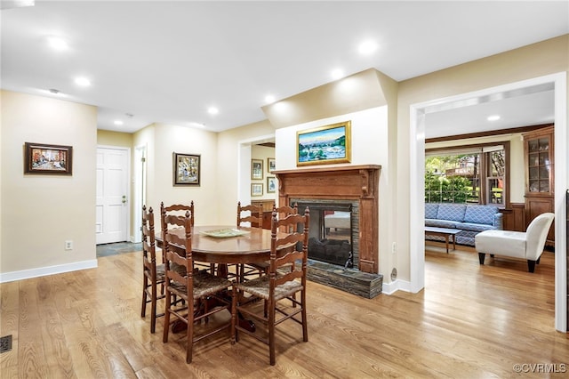 dining room featuring recessed lighting, a multi sided fireplace, baseboards, and light wood finished floors