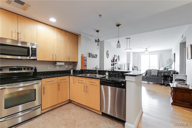 kitchen featuring appliances with stainless steel finishes, a sink, visible vents, a peninsula, and open floor plan