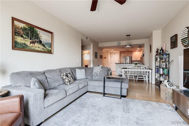 living area featuring visible vents, a ceiling fan, and light wood finished floors