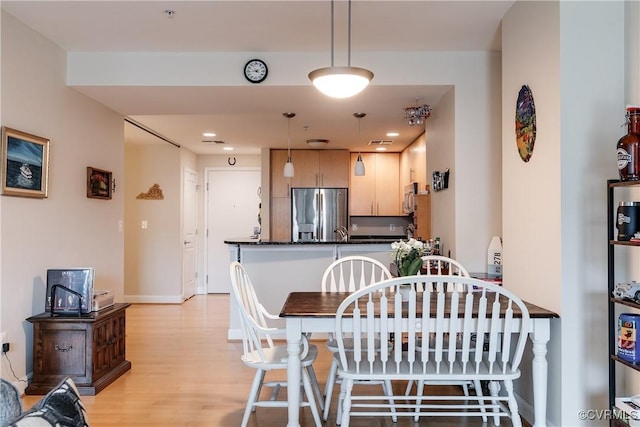 dining room with visible vents, light wood-style flooring, and baseboards
