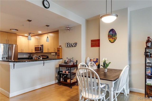dining room with recessed lighting, light wood-style flooring, and baseboards