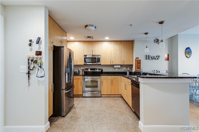 kitchen with hanging light fixtures, light brown cabinets, appliances with stainless steel finishes, a sink, and a peninsula
