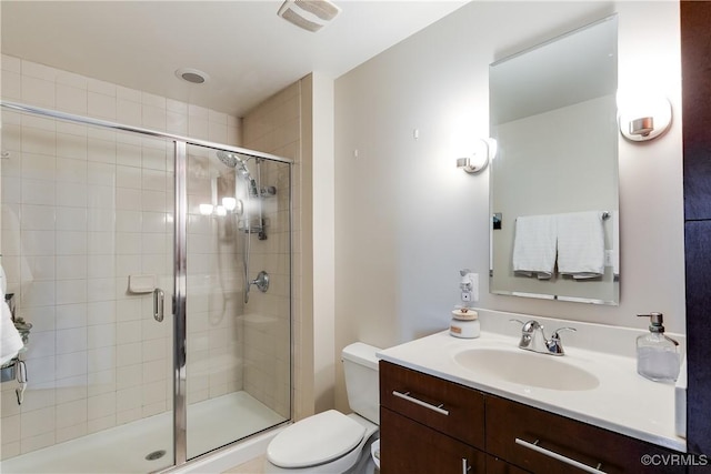 bathroom featuring toilet, visible vents, a shower stall, and vanity