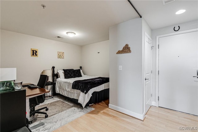 bedroom featuring baseboards, visible vents, and wood finished floors