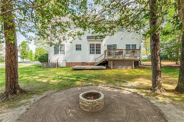 back of house with a lawn, a fire pit, and a wooden deck