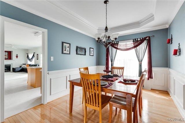 dining area featuring a decorative wall, wainscoting, and light wood-style floors