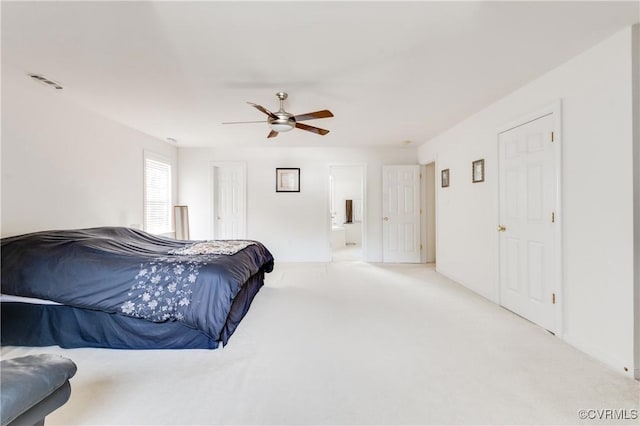 bedroom with ceiling fan, visible vents, light carpet, and ensuite bath