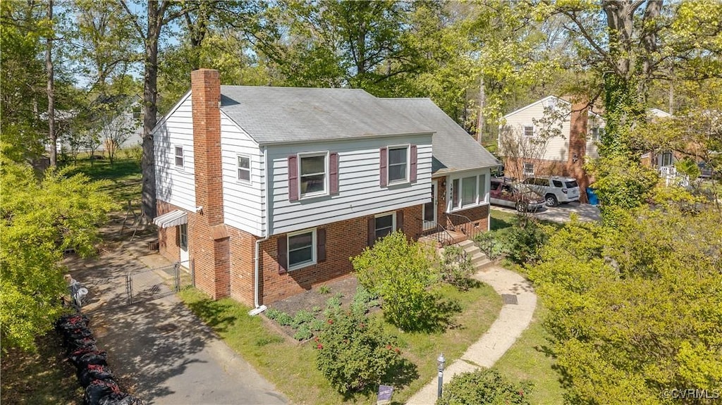 view of front of home with a chimney and brick siding