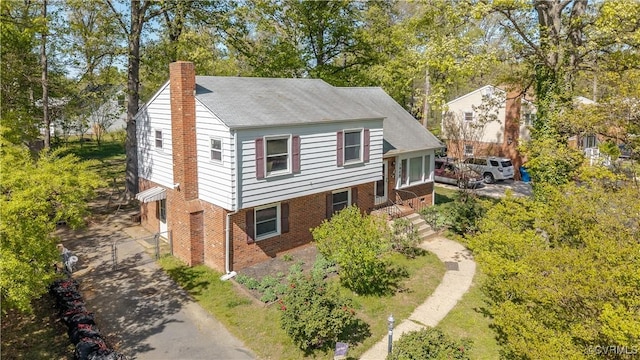 view of front of home with a chimney and brick siding