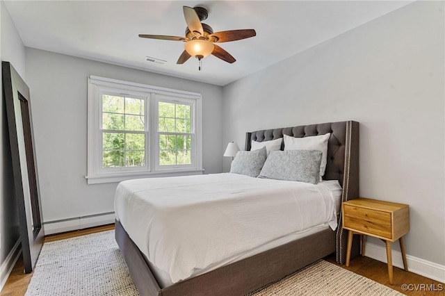 bedroom featuring ceiling fan, visible vents, baseboards, a baseboard radiator, and light wood-style flooring