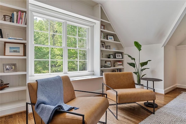 sitting room featuring baseboards, wood finished floors, vaulted ceiling, and built in shelves