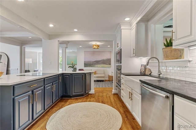 kitchen with appliances with stainless steel finishes, a sink, a center island, white cabinetry, and light wood-type flooring