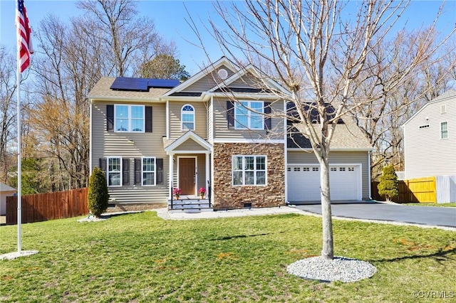 craftsman-style home with roof mounted solar panels, driveway, a front yard, and fence