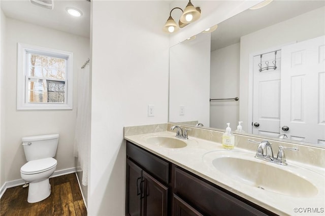 full bathroom featuring double vanity, wood finished floors, toilet, and a sink