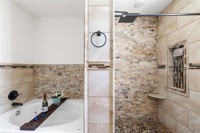 bathroom featuring a bath, tile walls, and a tile shower