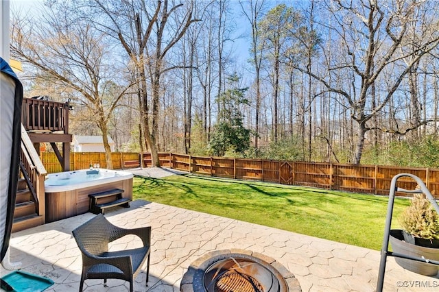 view of patio / terrace with a fenced backyard, a hot tub, and an outdoor fire pit