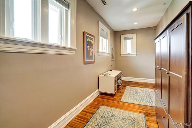 hallway with visible vents, wood finished floors, baseboards, and recessed lighting