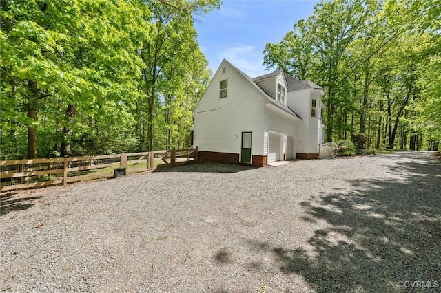 view of side of property with fence and gravel driveway