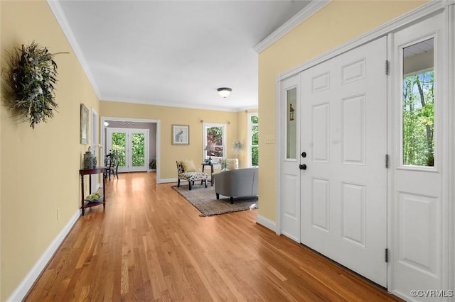 foyer entrance featuring crown molding, baseboards, and light wood-style flooring