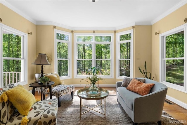 sunroom / solarium featuring baseboards, visible vents, ornamental molding, and wood finished floors