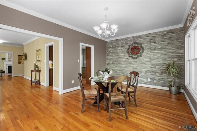 dining area with an inviting chandelier, ornamental molding, and light wood-style flooring