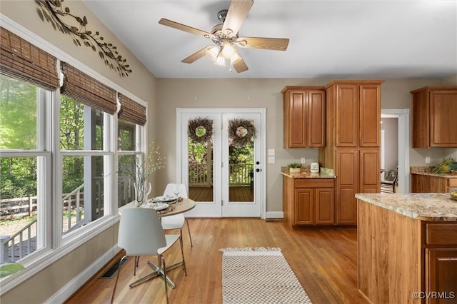 interior space with baseboards, ceiling fan, light wood finished floors, and a wealth of natural light