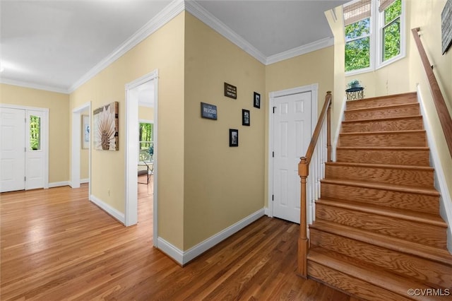 foyer with crown molding, baseboards, light wood finished floors, and stairs