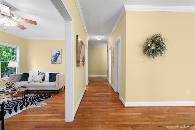 hall with crown molding, baseboards, and wood finished floors