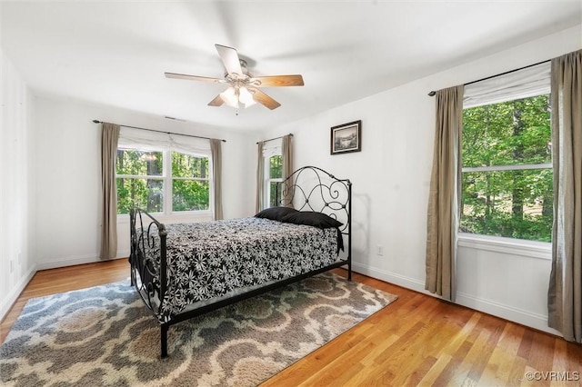 bedroom with baseboards, multiple windows, and wood finished floors