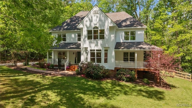 view of front facade featuring roof with shingles, fence, covered porch, and a front yard