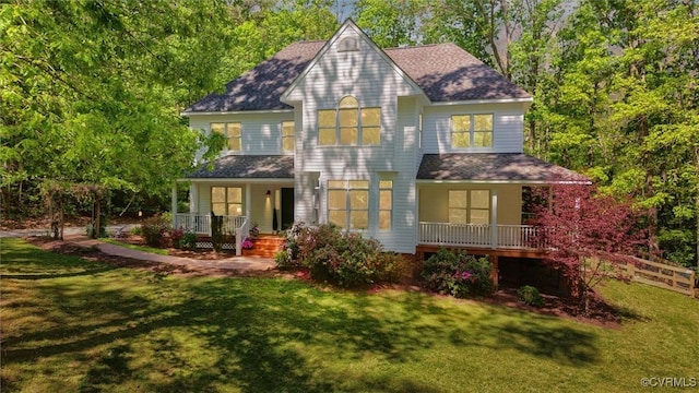 rear view of property with a shingled roof, a yard, and covered porch