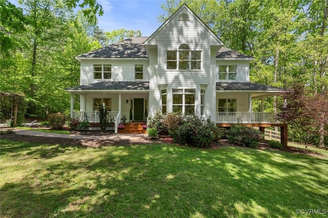 back of house with covered porch, a yard, and a shingled roof