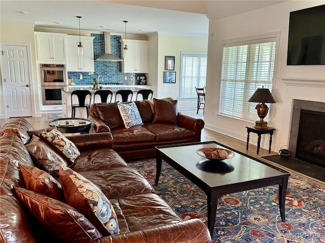 living area with baseboards, a fireplace with flush hearth, and light wood-style flooring