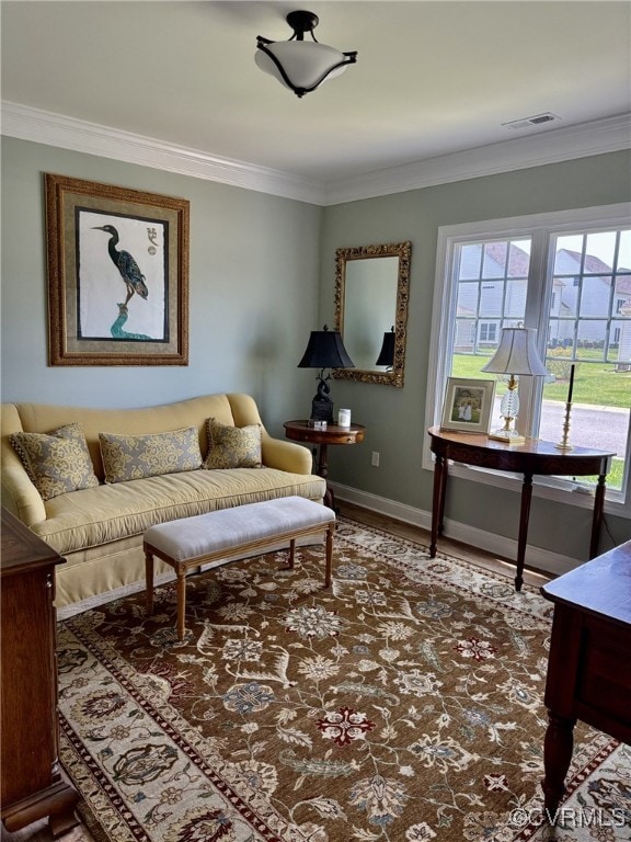 living area with crown molding, baseboards, visible vents, and wood finished floors
