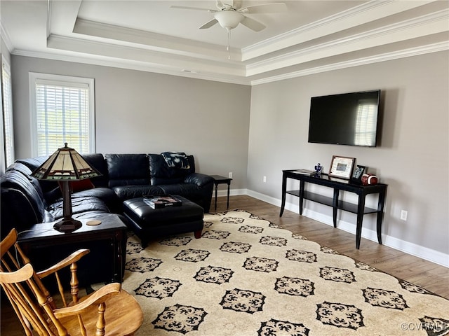 living room with crown molding, ceiling fan, wood finished floors, and a tray ceiling